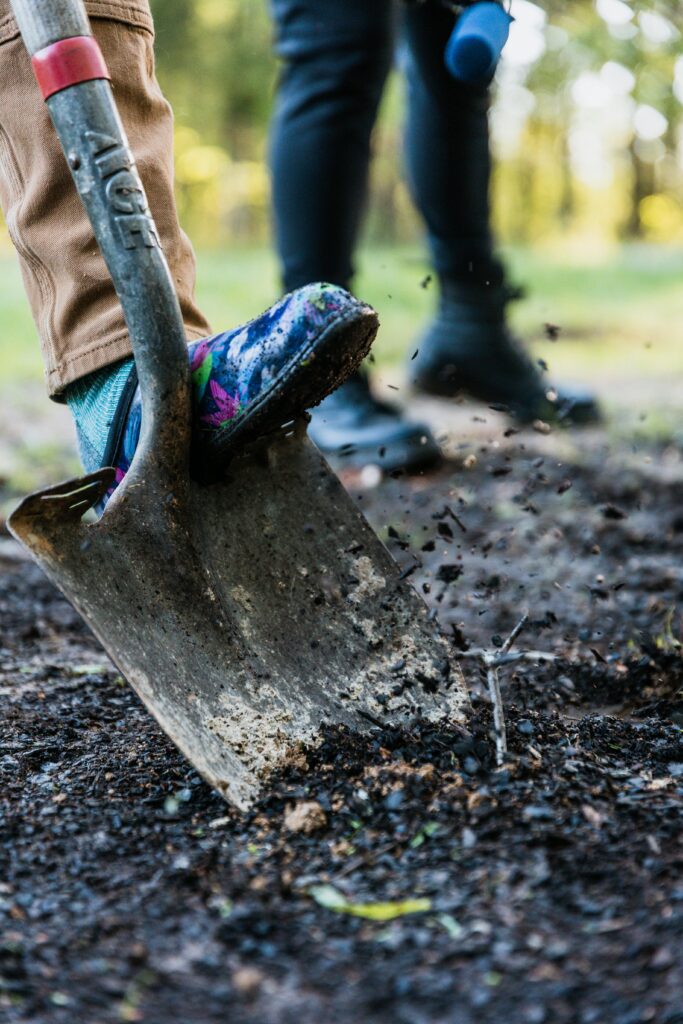 Vibrant close-up of a shovel with colorful shoe digging in the soil, outdoors.